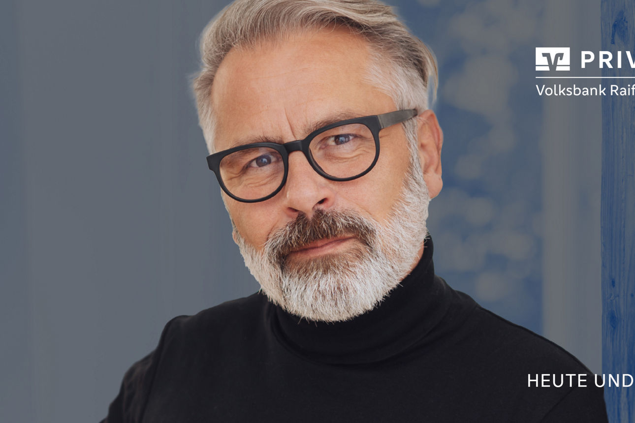 Mann mit Brille schaut auf das Modell einer Immobilie