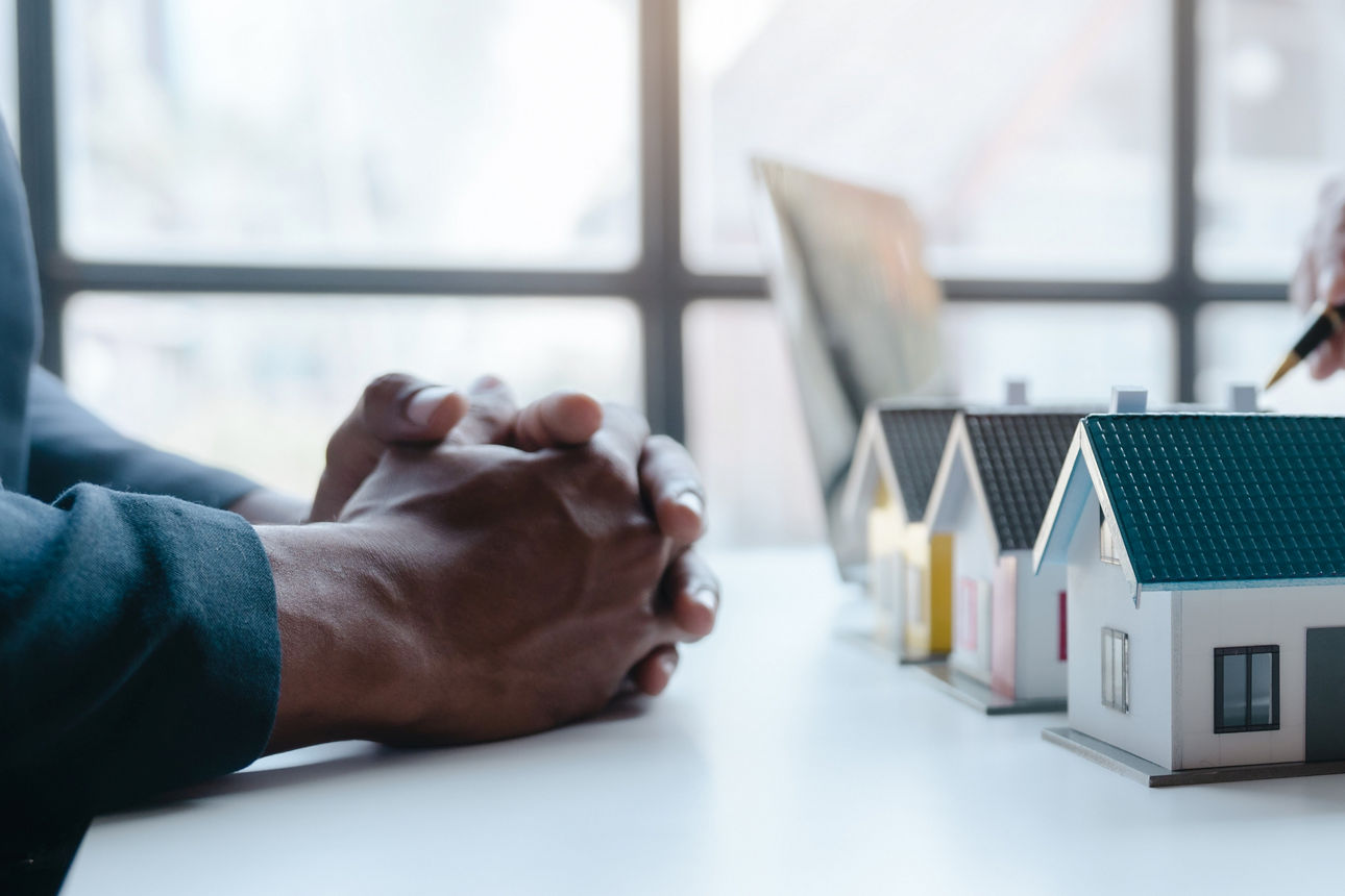 Immobilienberatung mit Modellhäusern und Schlüsseln auf einem Tisch.