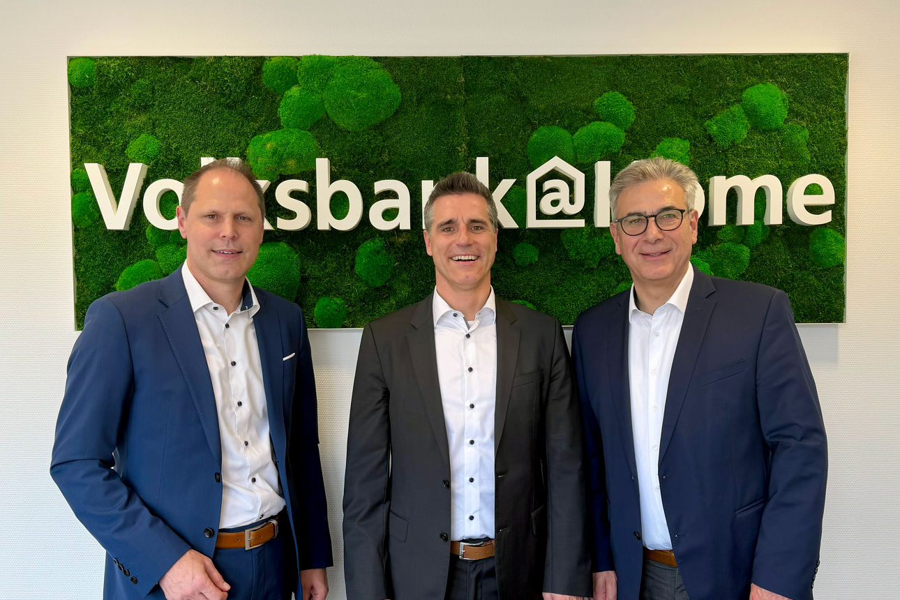 Drei Herren stehen vor dem Plakat von Volksbank@Home