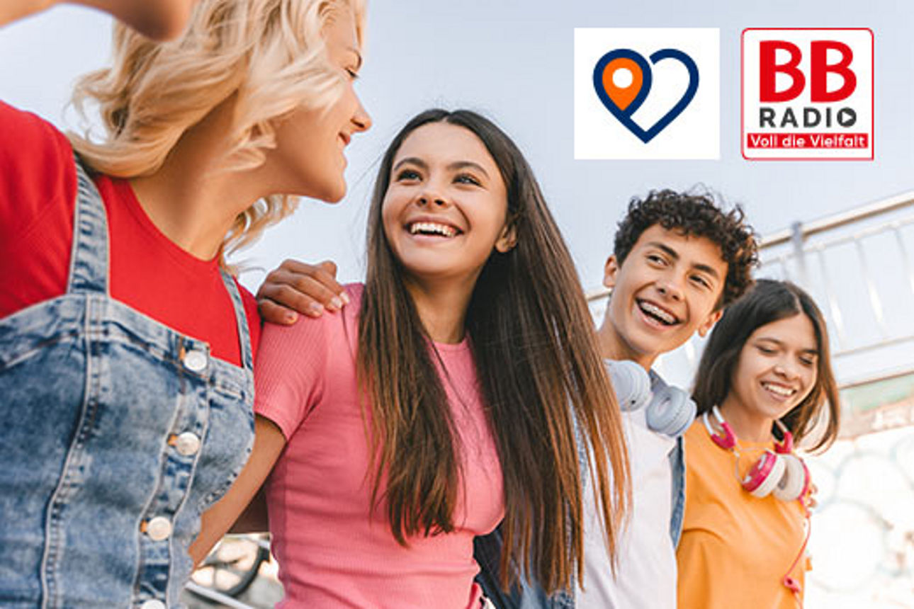 vier Jugendliche fassen sich an den Schultern und lachen