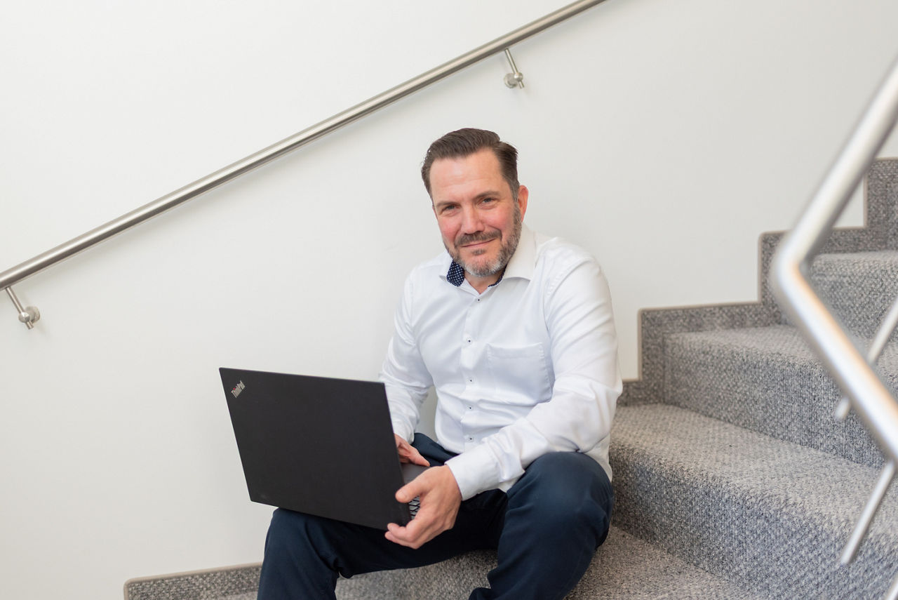 Ein Mann sitzt mit seinem Laptop auf Treppenstufen.