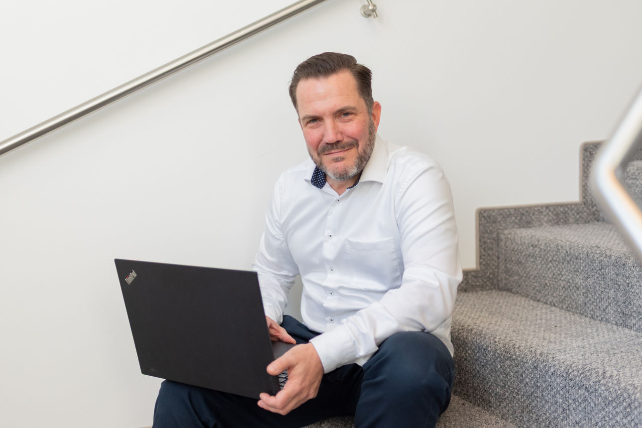 Ein Mann sitzt mit seinem Laptop auf Treppenstufen.