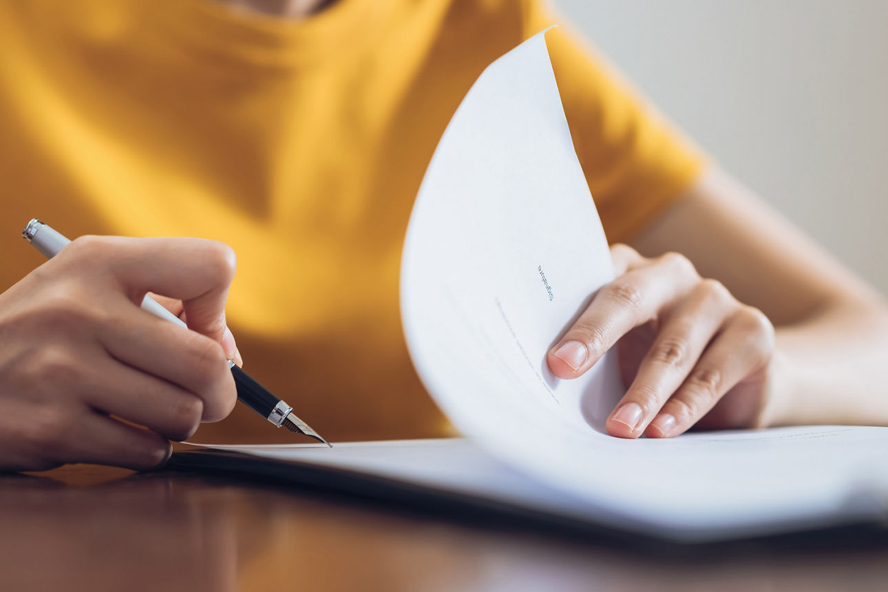 Frau schreibt mit Füller auf ein Blatt Papier