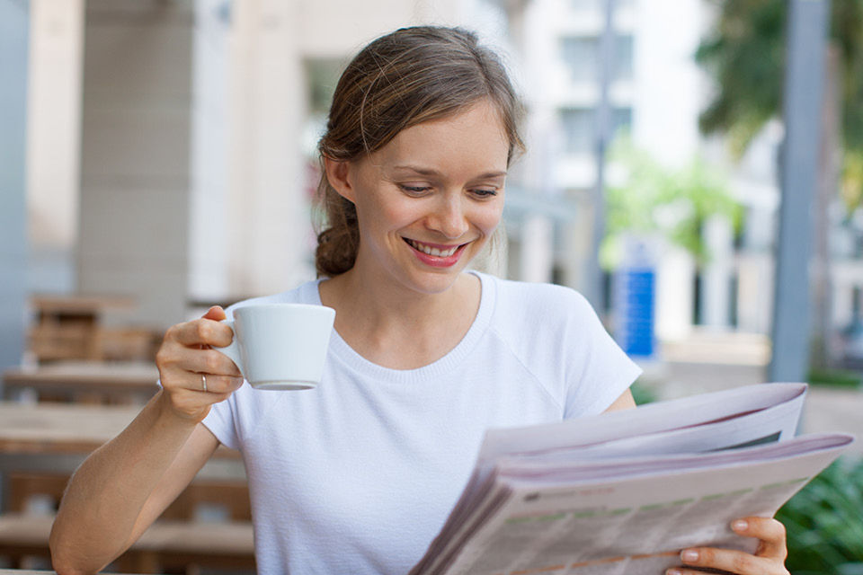 Frau liest im Cafe Zeitung