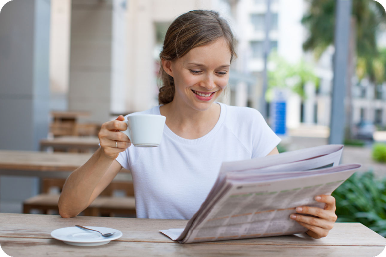 Frau sitzt im Cafe und liest Zeitung