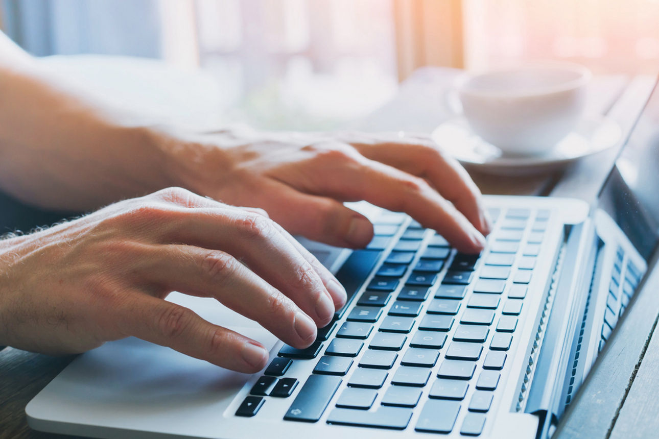 Hände schreiben auf Tastatur vom Laptop