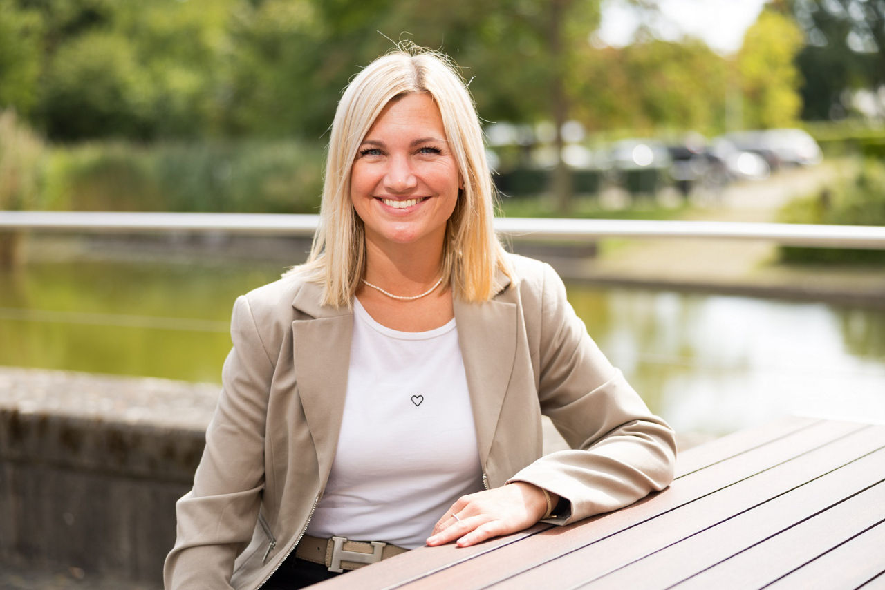 Charline Lange aus dem Team Betriebliches Gesundheitsmanagement sitzt draußen am Tisch.