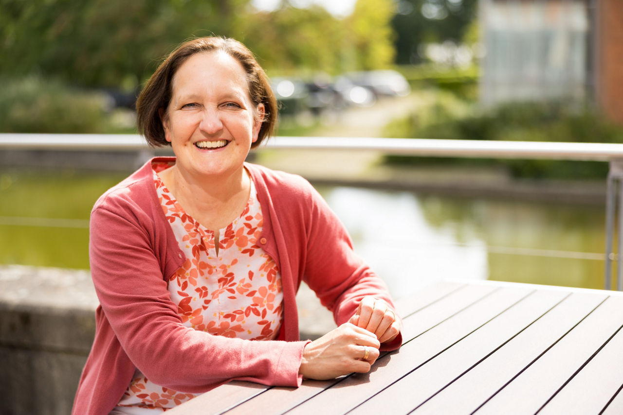 Dagmar Brinkmann aus dem Team Betriebliches Gesundheitsmanagement sitzt draußen am Tisch.