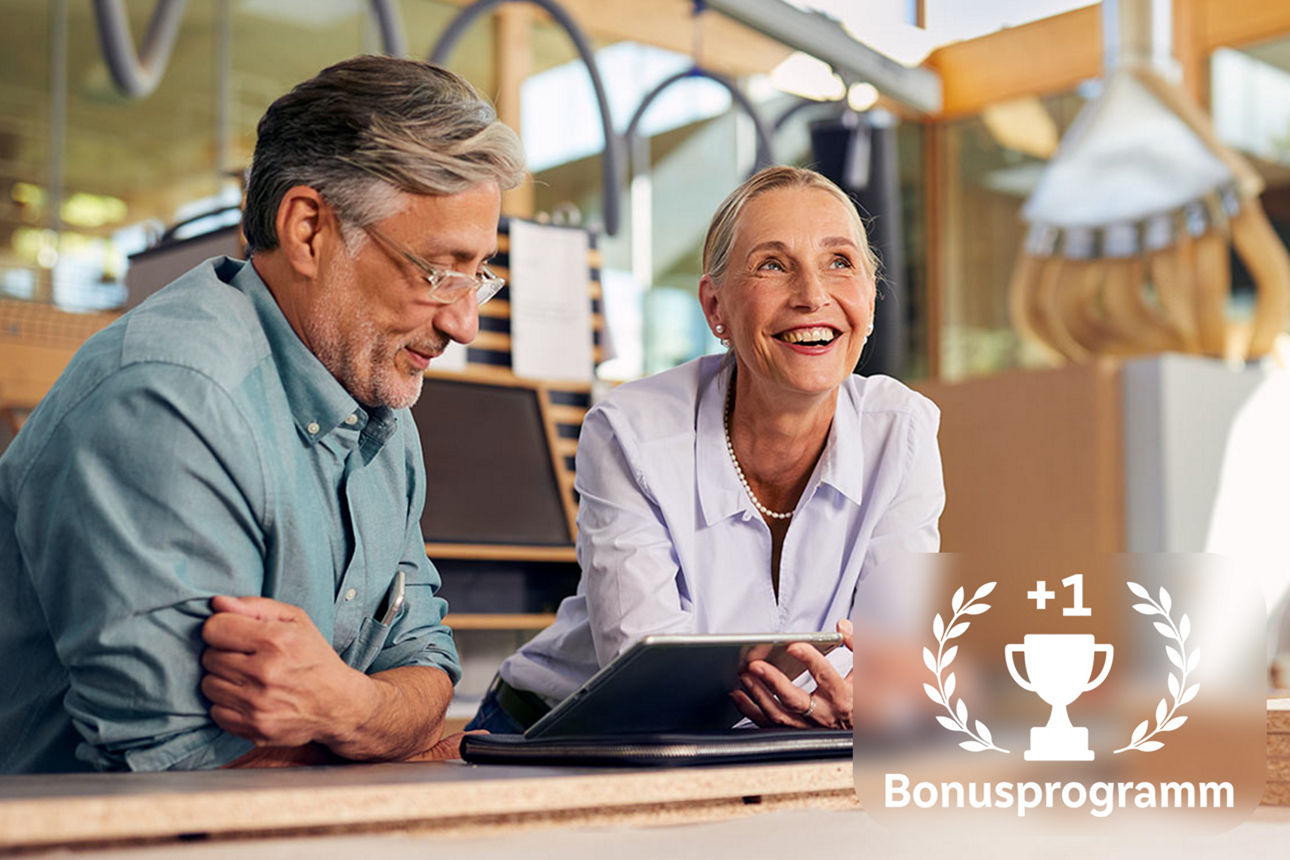 Geschäftsführerin und Betriebsleiter lachend mit Tablet an einem Arbeitstisch