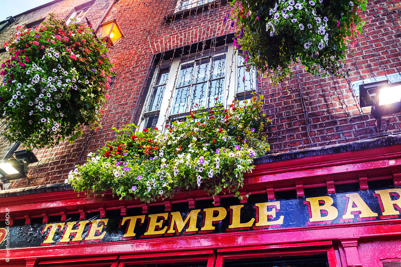 Rote Fassade der berühmten Temple Bar in Dublin mit bunten Blumenkästen und typisch irischer Pub-Atmosphäre.