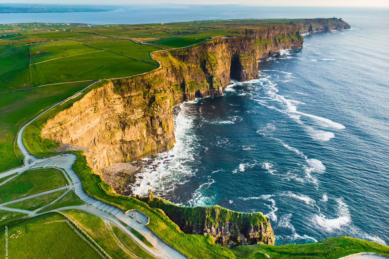 Blick auf die imposanten Cliffs of Moher in Irland. Steile Felsklippen ragen über dem Atlantik auf und werden von grünen Wiesen gesäumt.