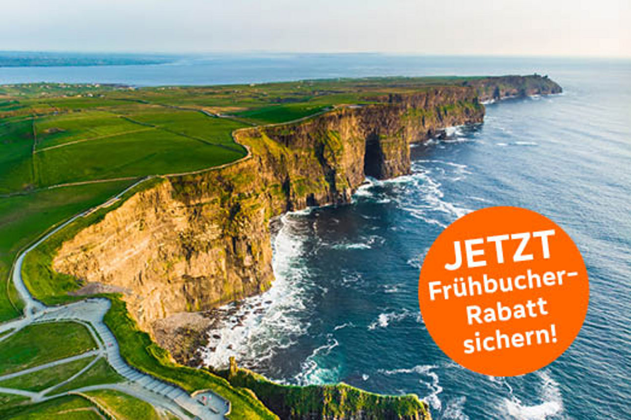 Blick auf die imposanten Cliffs of Moher in Irland. Steile Felsklippen ragen über dem Atlantik auf und werden von grünen Wiesen gesäumt.
