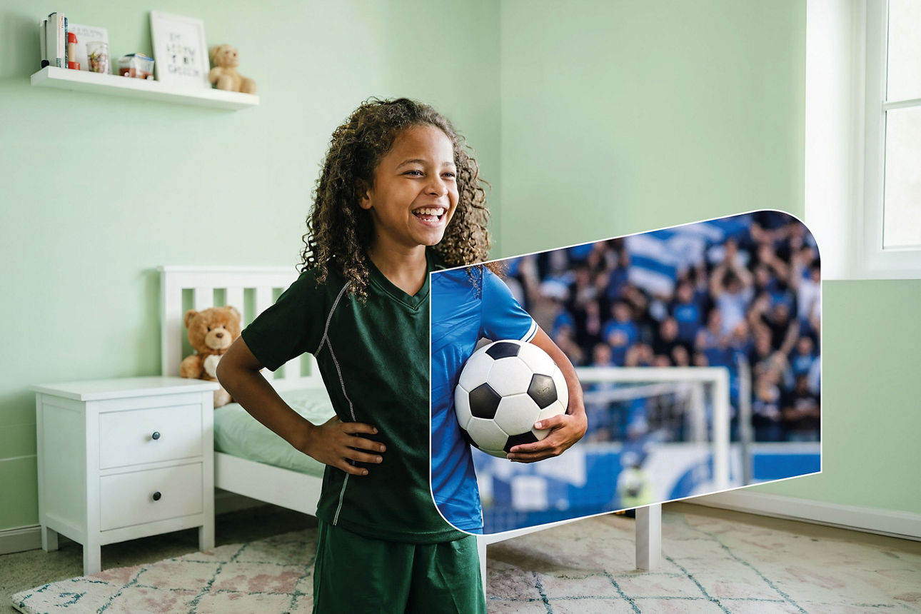 Mädchen steht in einem Zimmer und hält einen Fußball in der Hand. Ein Teil des Hintergrunds sieht aus wie ein Fußballstadion.