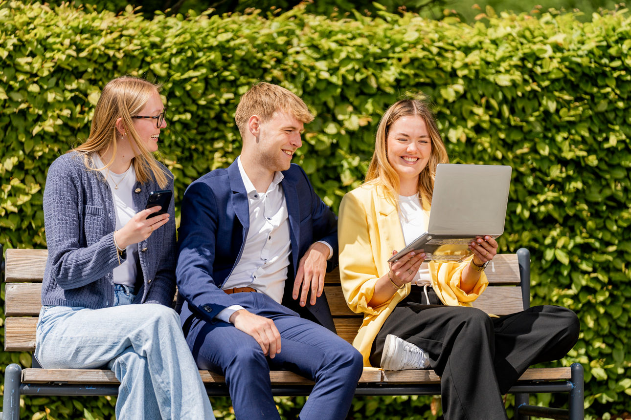 drei junge Erwachsene sitzen auf einer Bank und profitiert von den Services & Mehrwerten seiner Bank