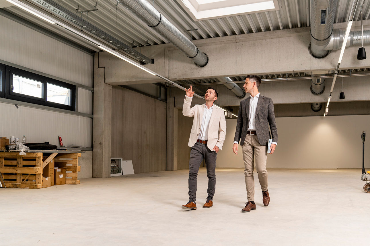 zwei Männer gehen in einer leeren Lagerhalle