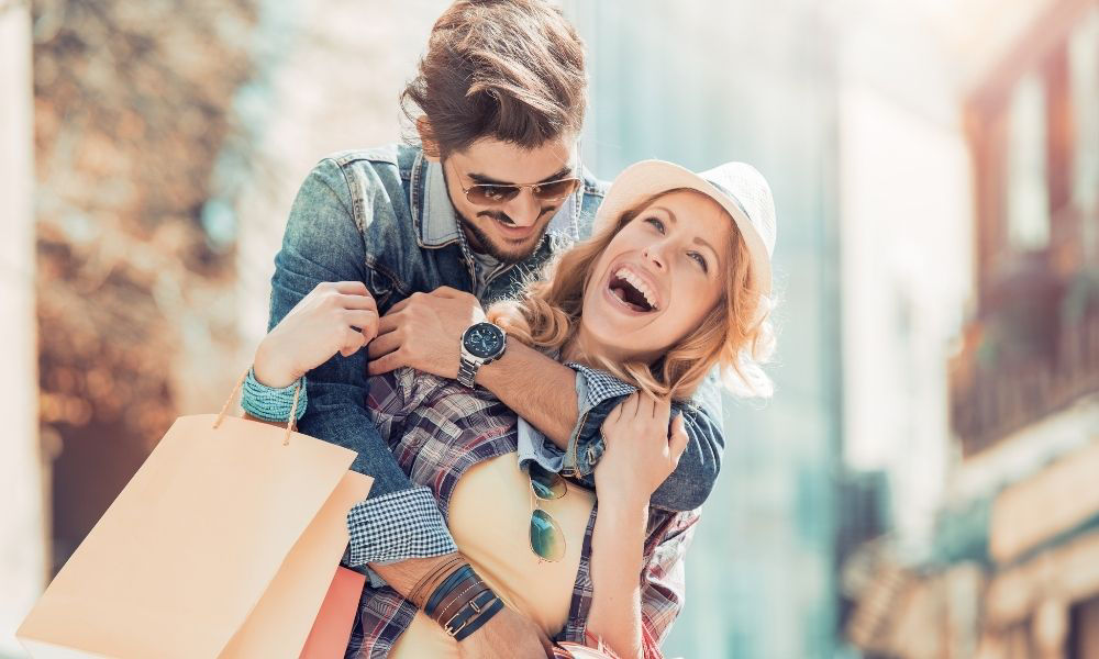 Junges Liebespaar freudestrahlend auf der Shoppingtour