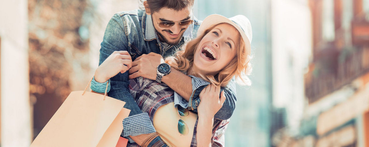 Junges Liebespaar freudestrahlend auf der Shoppingtour