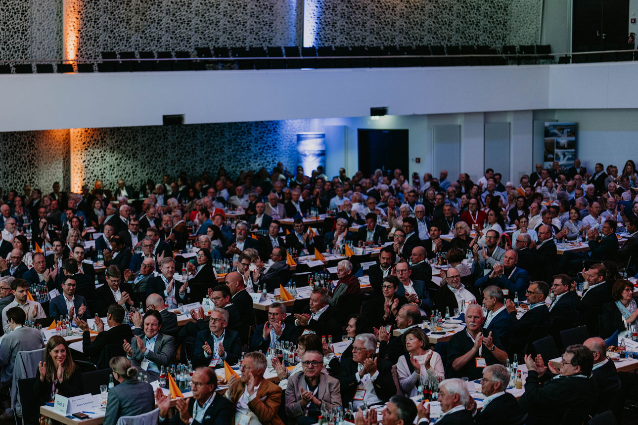 Viele Personen in einem Saal an Tischen sitzend
