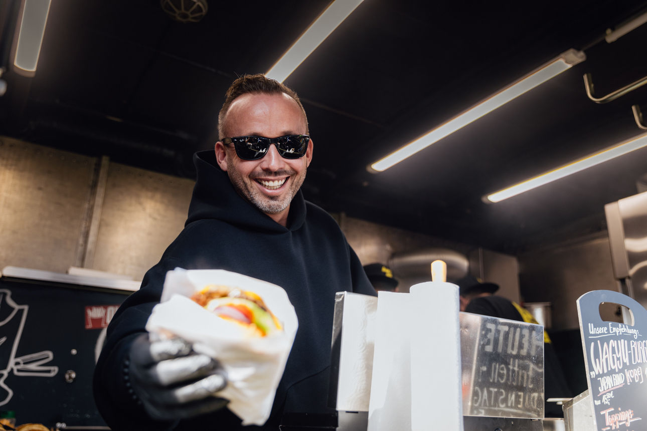 Inhaber Christian Kohl von Jack’s Tasty Foodtrucks reicht frisch zubereitetes Streetfood am Foodtruck aus.
