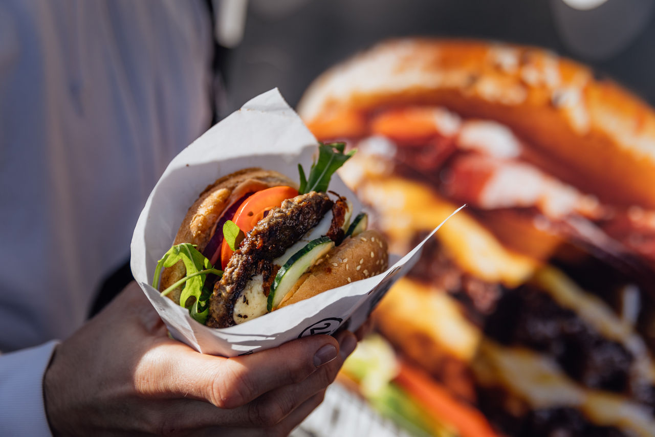Burger von Jack’s Tasty Foodtrucks, serviert direkt am Foodtruck vor einem großen Produktmotiv.