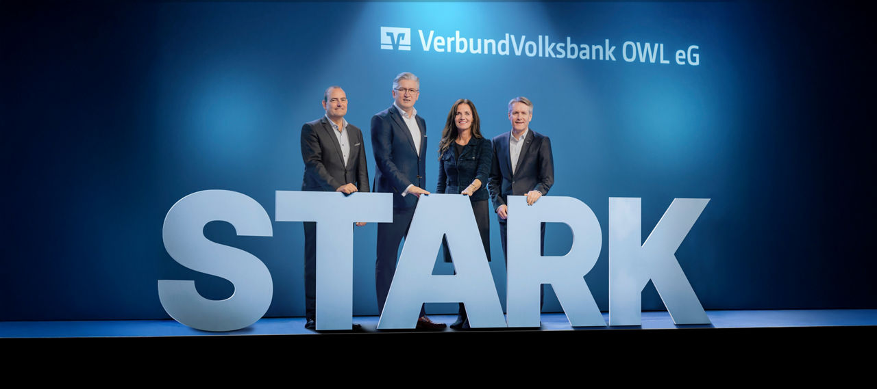 Der Vorstand der VerbundVolksbank OWL auf einer Bühne mit großen Buchstaben, die das Wort "STARK" darstellen