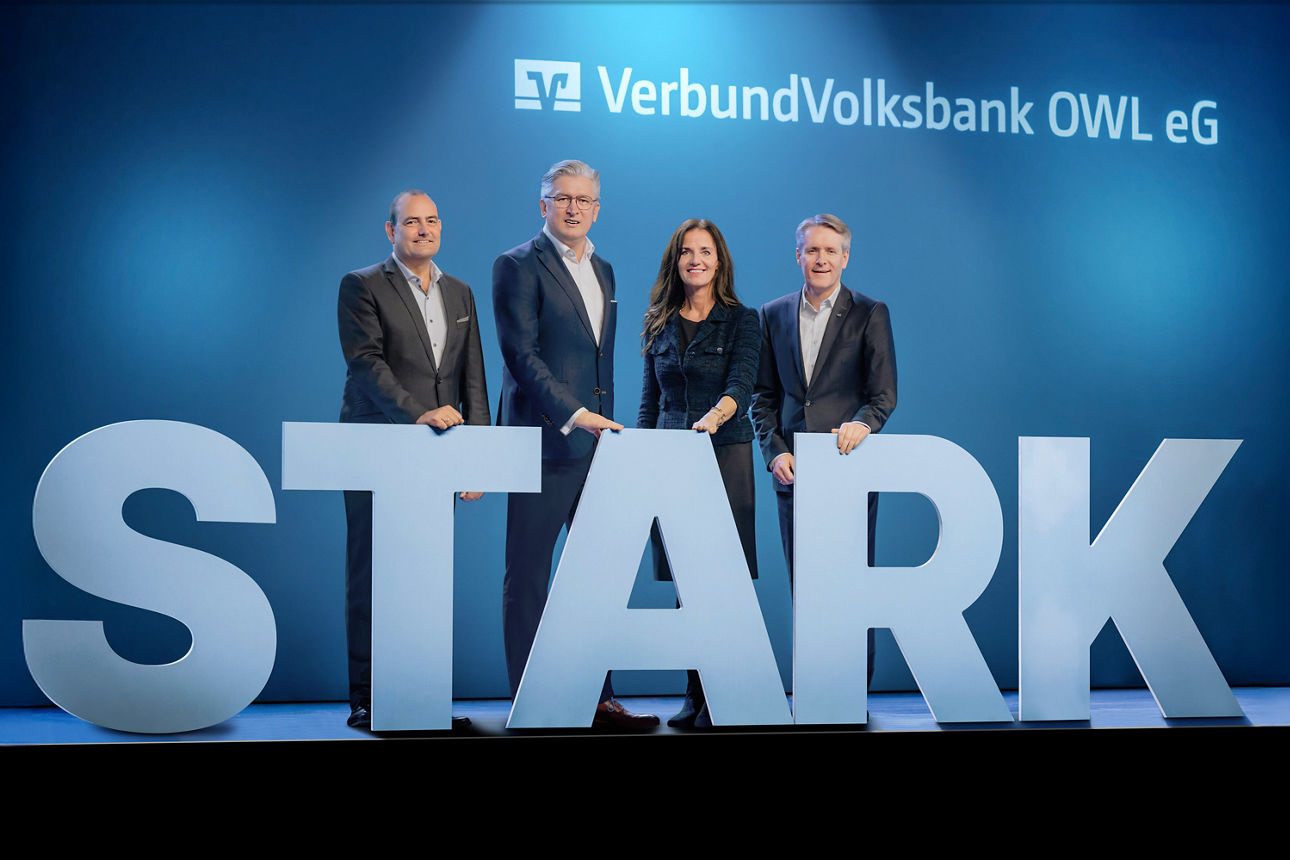 Der Vorstand der VerbundVolksbank OWL auf einer Bühne mit großen Buchstaben, die das Wort "STARK" darstellen