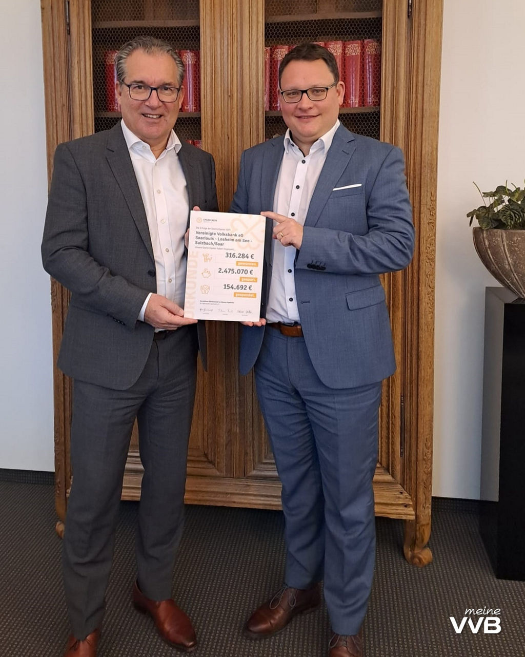 Zwei Herren des Vorstandes halten eine Urkunde zwischen sich in den Händen