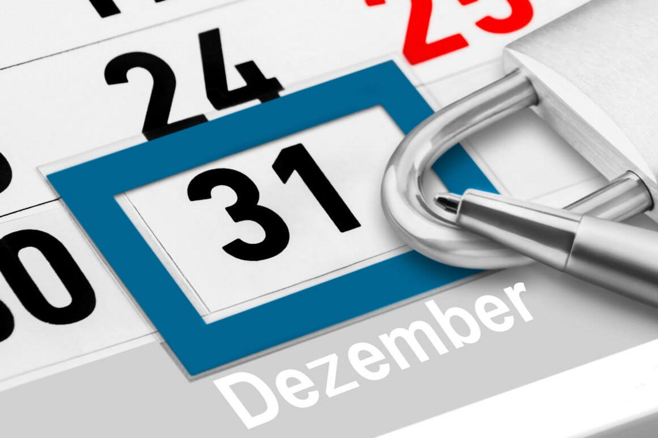 Kalenderblatt zeigt den 31. Dezember, umrahmt von einem blauen Rahmen, daneben ein geöffnetes Vorhängeschloss aus Metall.