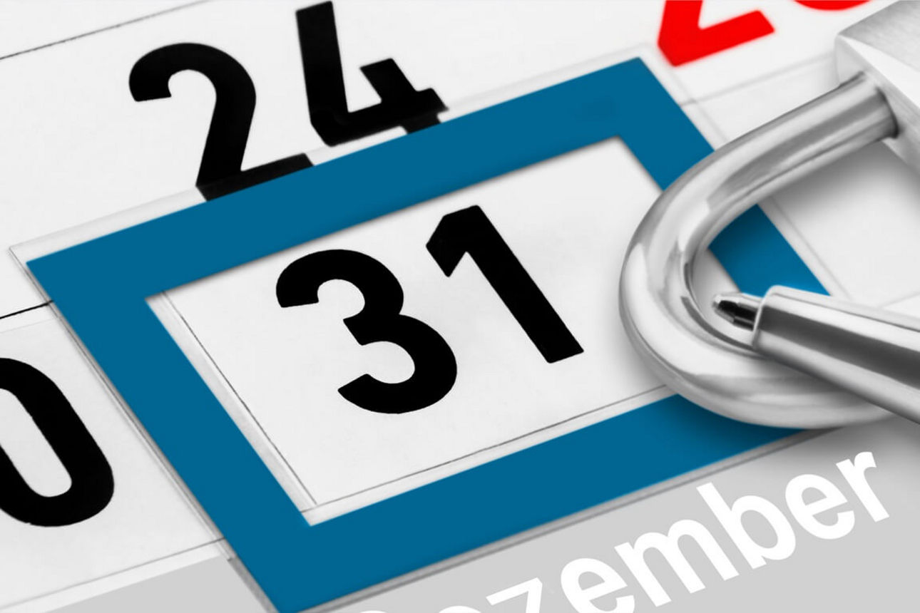 Kalenderblatt zeigt den 31. Dezember, umrahmt von einem blauen Rahmen, daneben ein geöffnets Vorhängeschloss aus Metall.