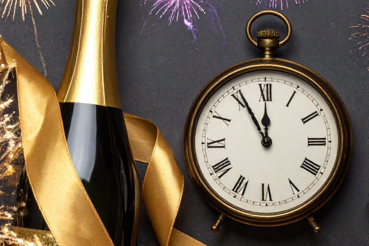 Uhr neben Feuerwerk und Sekt