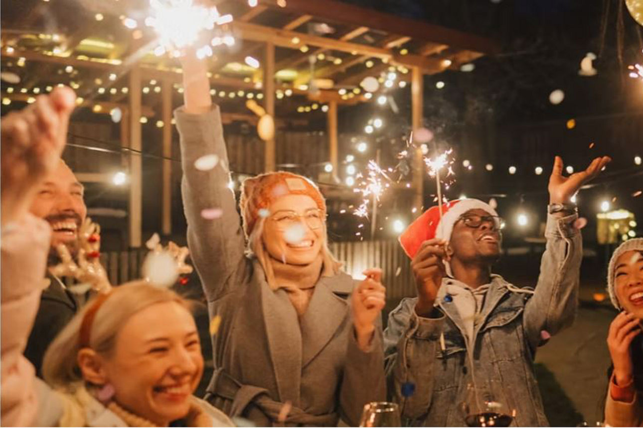 Menschen feiern lachend mit Wunderkerzen Sylvester