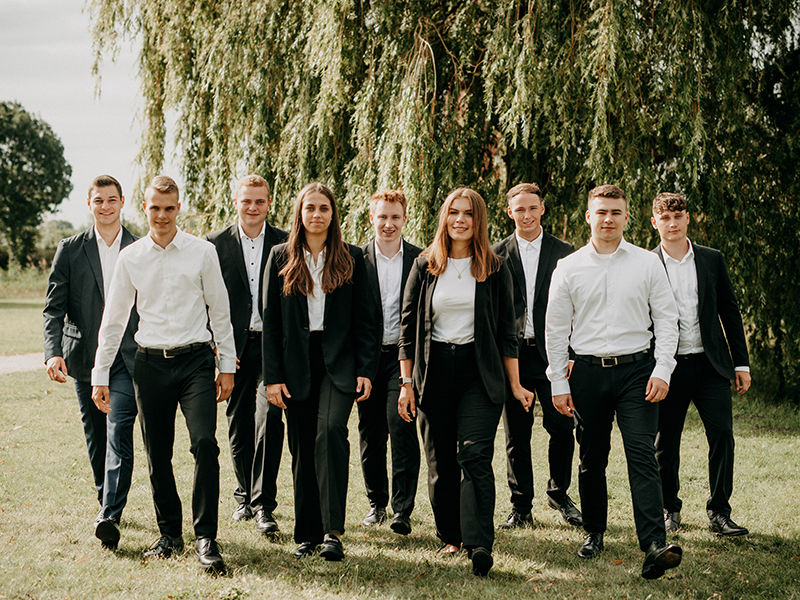 Eine Gruppe mit Azubildenden vor einem grünen Baum.