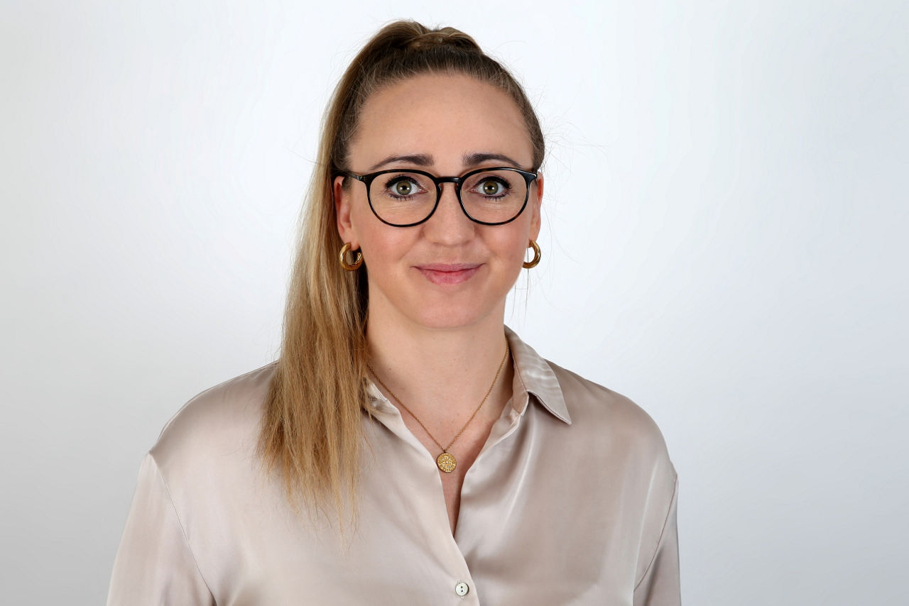 Eine lächelnder Frau schaut in die Kamera.