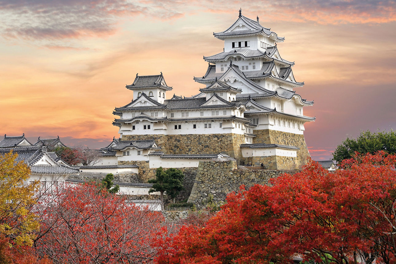 Schloss Himeji und rote Ahornblätter im Abendlicht und Dämmerungshimmel in der Stadt Himeji, Präfektur Hyogo, Japan.