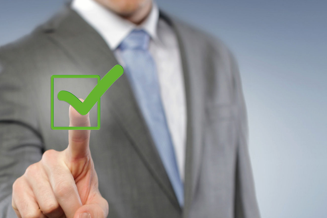 Mann, der einen grünen Haken mit dem Finger berührt. 