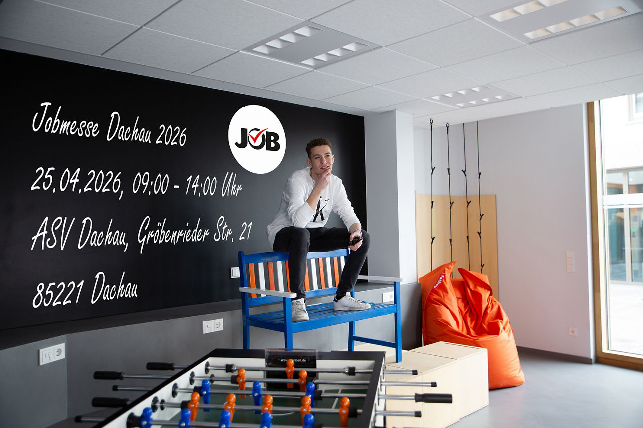 Ein junger Mann sitzt auf einer Holzbank vor einer Tafelwand