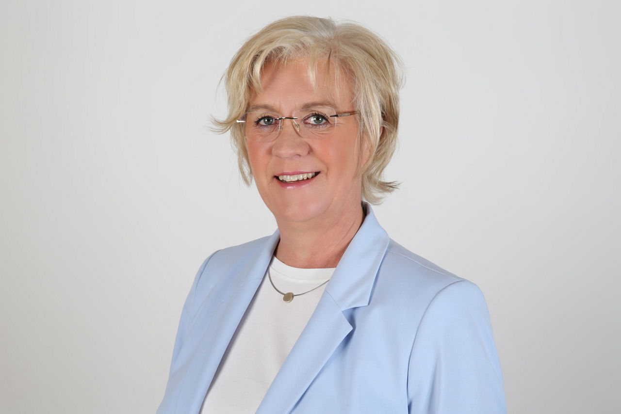  Eine lächelnder Frau schaut in die Kamera.