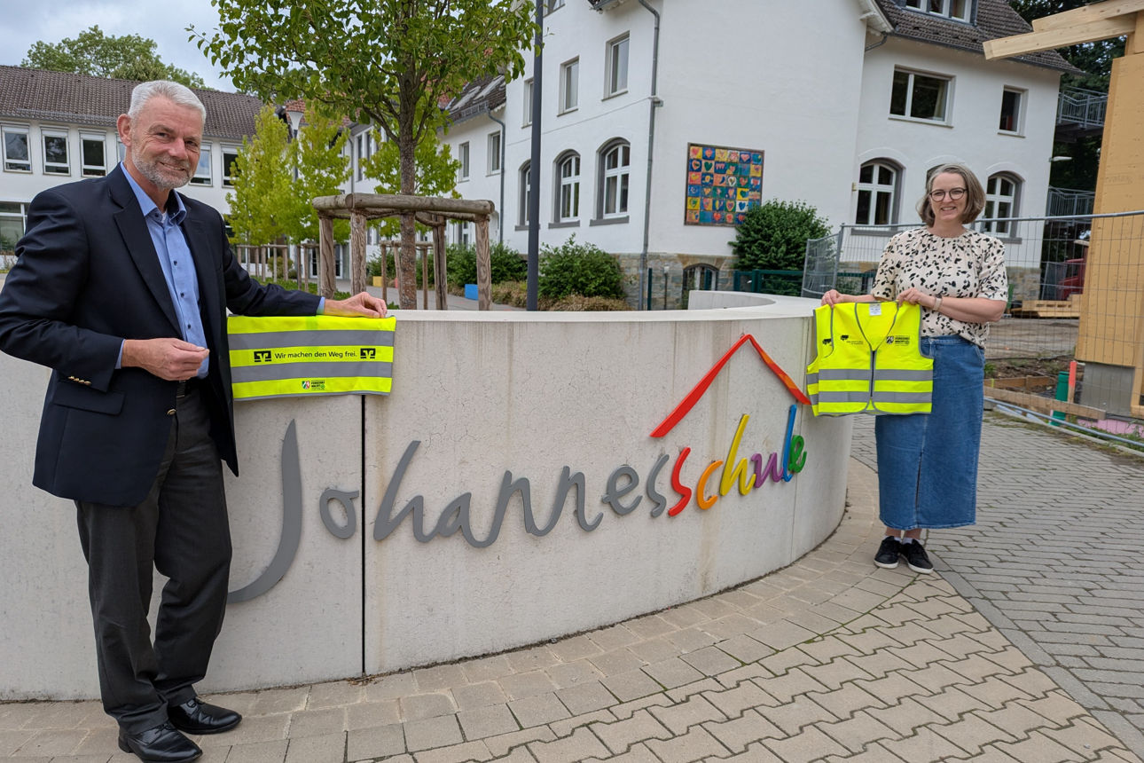 Zwei Personen vor der Johannesschule in Sassenberg, mit jeweils einer Signalweste 