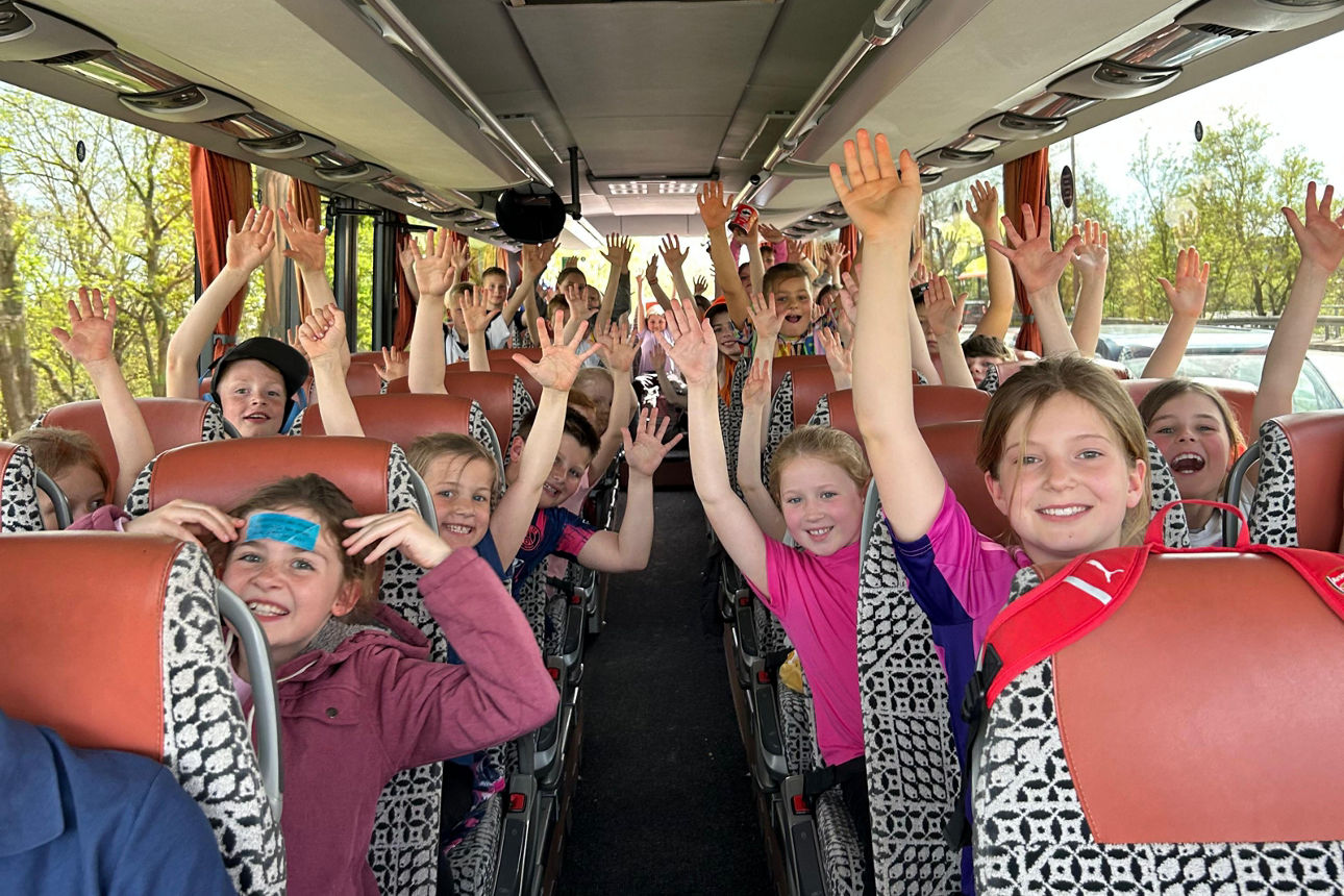 Glückliche Kinder heben die Arme in die Luft in einem Bus.
