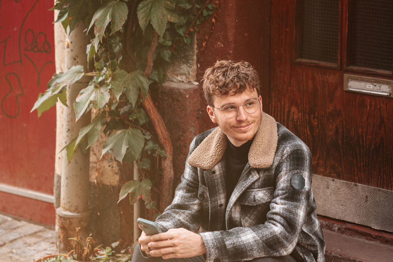 Mann sitzt auf der Treppe und hat ein Handy in der Hand