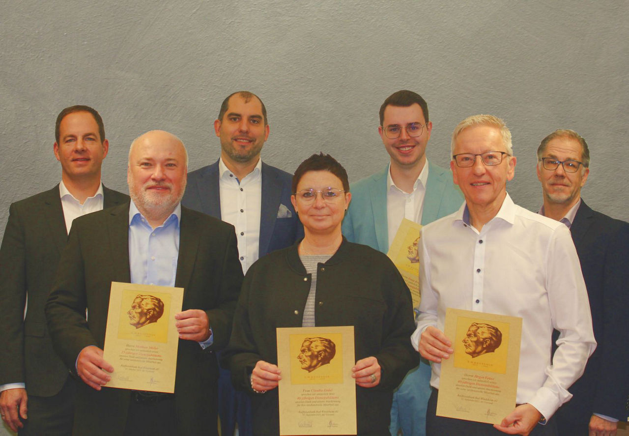 Vorm dem Altar in der Kirche steht eine evang. Pfarrerin in links und rechts jeweils ein Mann und eine Frau. Alle lächeln in 