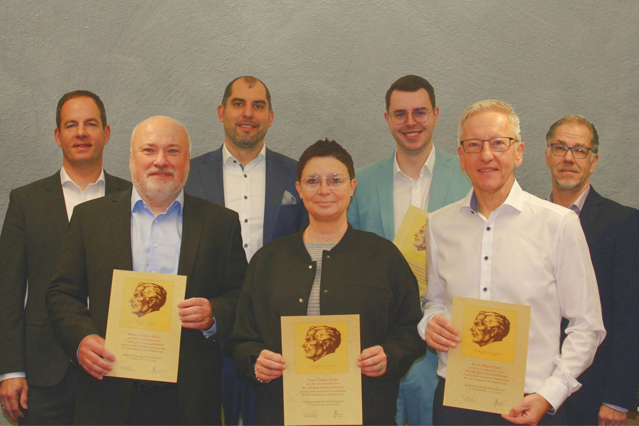 vorne stehen links und rechts ein Mann, mittig eine Frau, dahinter 2 Männer und zeigen gelb-braune Urkunden in die Kamera lin