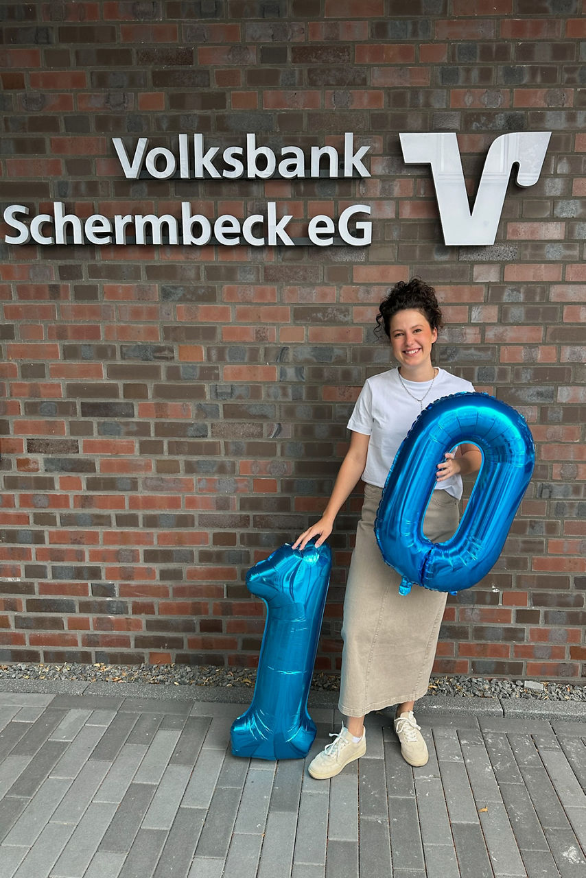 Jubilarin Sophie Bienbeck vor einer Wand mit den Ballonzahlen 1 und 0 in den Händen.