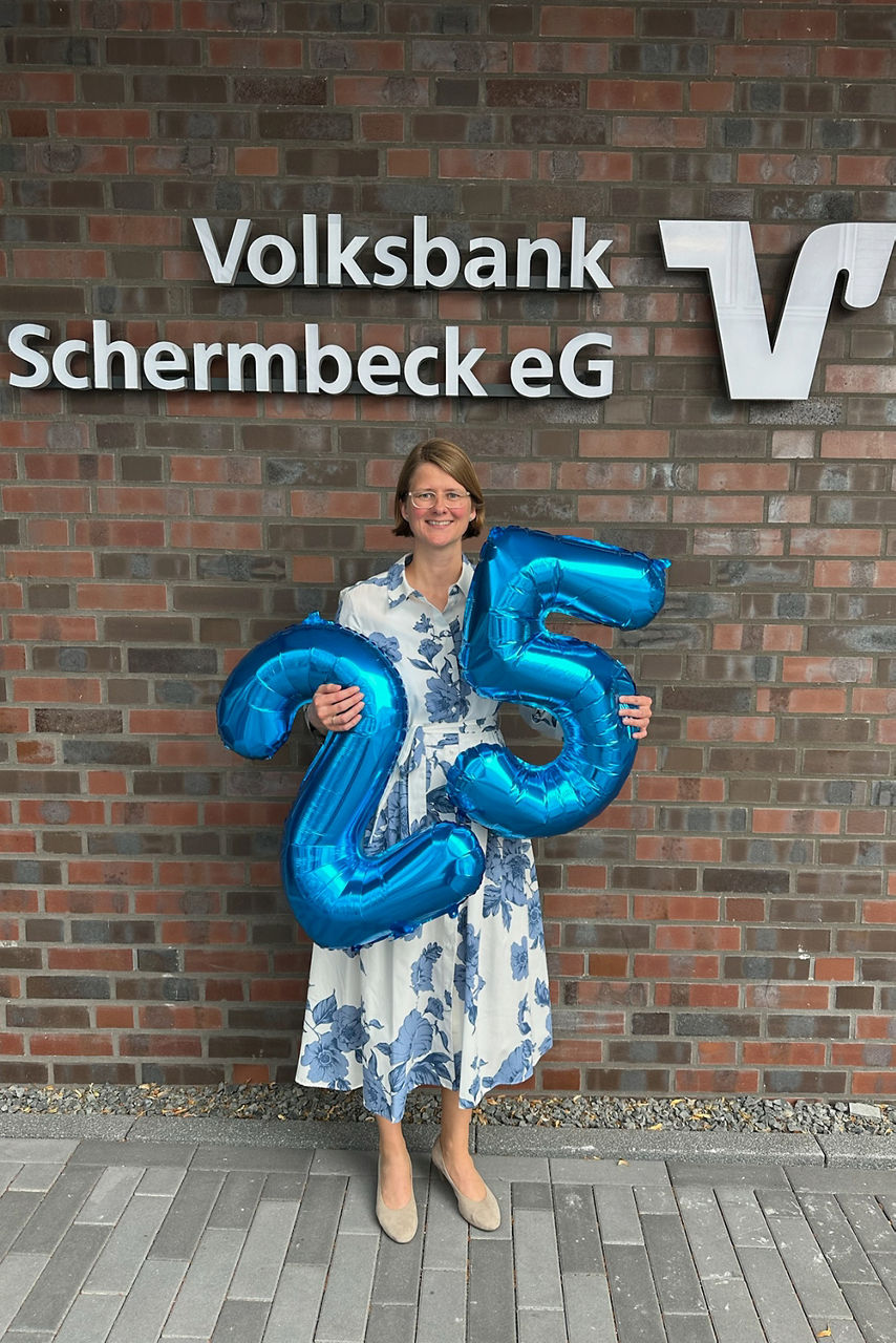 Jubilarin Sonja Krämer mit den blauen Ballonzahlen 2 und 5 in den Händen.