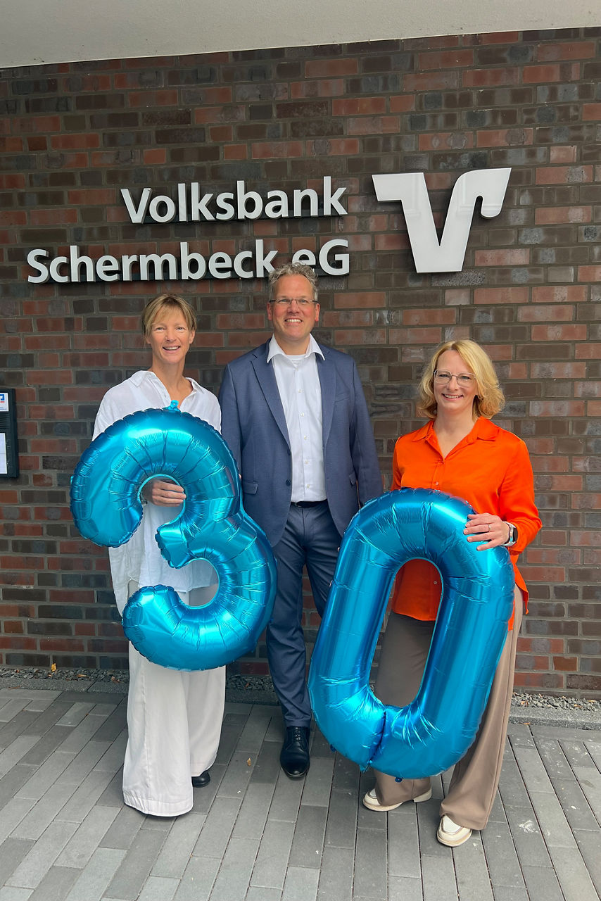 Jubilare Susanne Vogel, Heribert Triptrap und Eva Aehling mit den blauen Ballonzahlen 3 und 0.