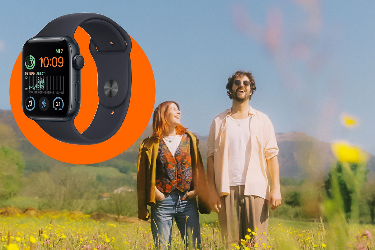 Ein Mann und eine Frau gehen über ein Feld. Im Vordergrunfd eine Apple Watch.