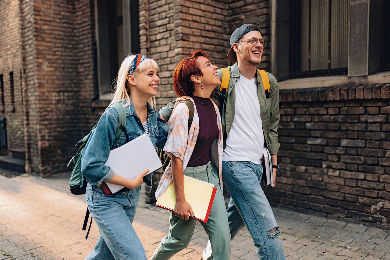 Drei Schüler laufen zusammen auf dem Gehweg