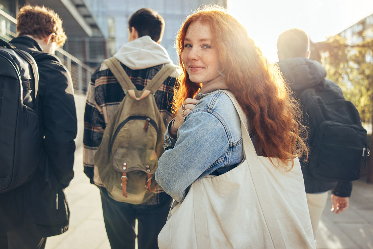 Eine Studentin blickt über die Schulter, während sie mit Freunden auf dem Weg zum Unterricht in der Schule ist.
