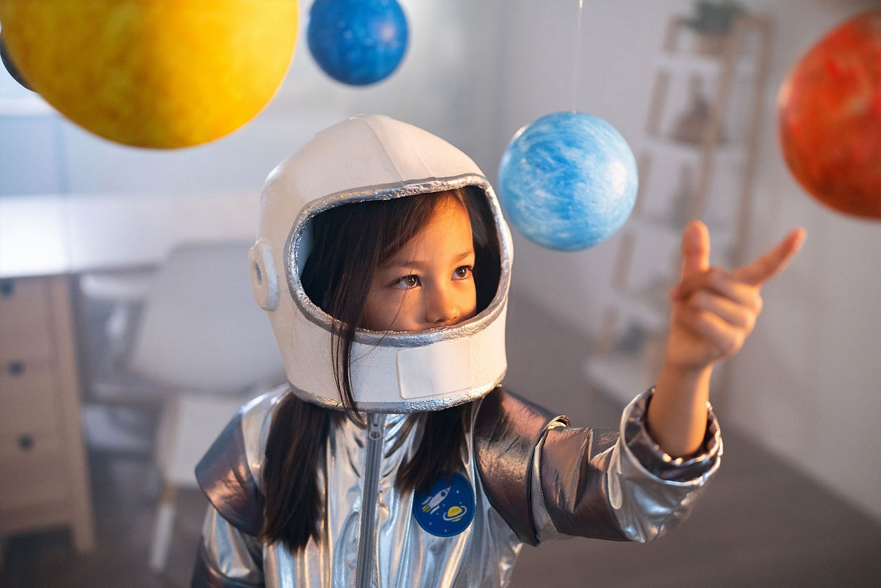 Mädchen im Astronautenkostüm spielt mit dem Sonnensystem.