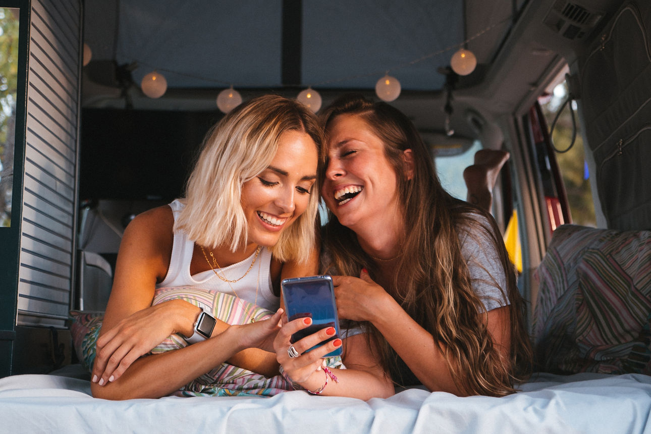 Zwei junge Frauen im Camper mit Smartphone